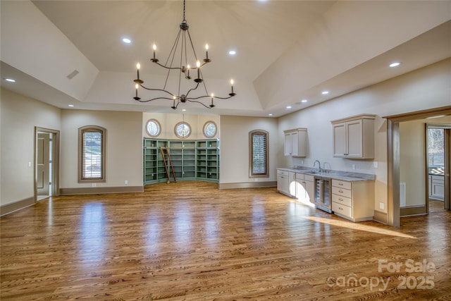 kitchen with a high ceiling, beverage cooler, white cabinetry, and plenty of natural light