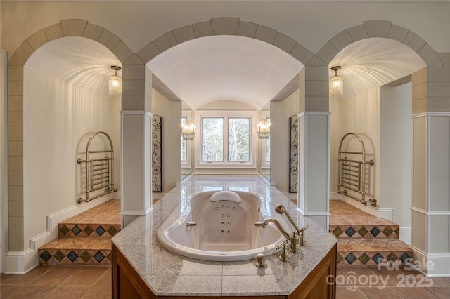 bathroom with lofted ceiling, tile patterned floors, sink, and a tub