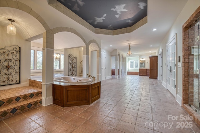 bathroom with a washtub, a raised ceiling, and tile patterned floors