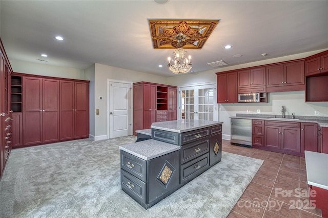 kitchen featuring appliances with stainless steel finishes, hanging light fixtures, a kitchen island, sink, and an inviting chandelier