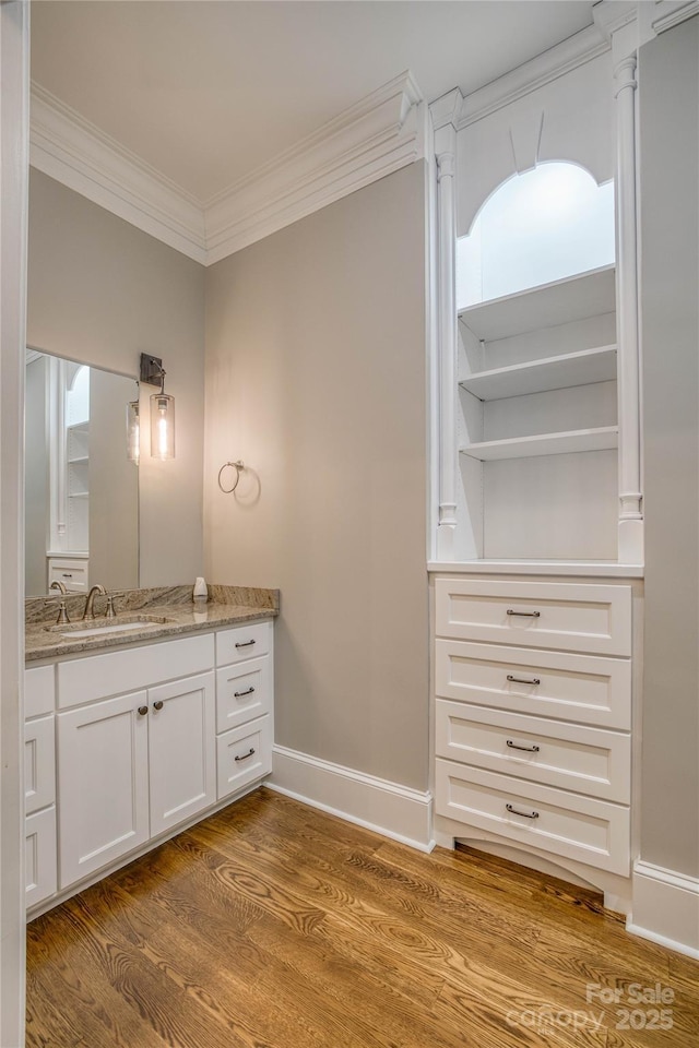 bathroom featuring hardwood / wood-style floors, crown molding, and vanity