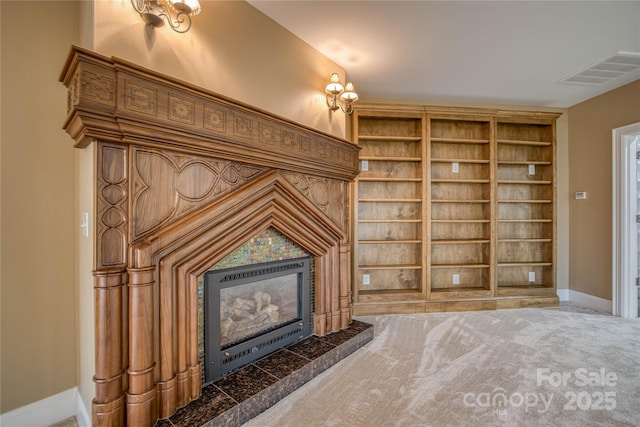 unfurnished living room featuring a tile fireplace, light carpet, and built in shelves