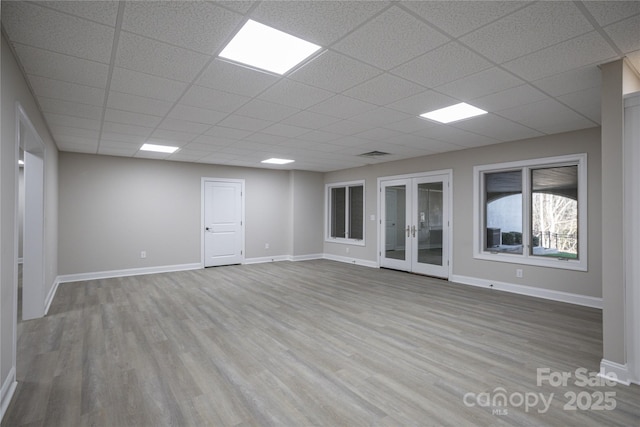 unfurnished room with a paneled ceiling, french doors, and light wood-type flooring