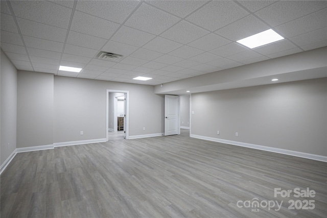 basement featuring a paneled ceiling and hardwood / wood-style flooring