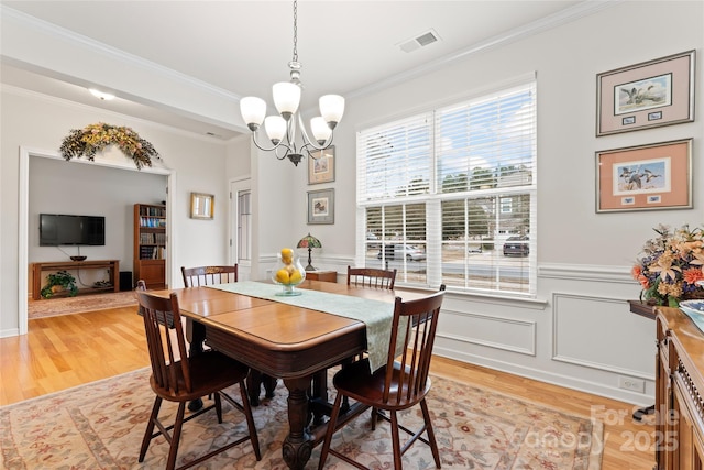 dining area featuring light hardwood / wood-style flooring, crown molding, and a chandelier