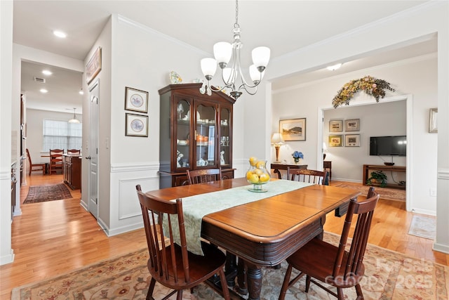 dining space with ornamental molding, light hardwood / wood-style flooring, and a chandelier