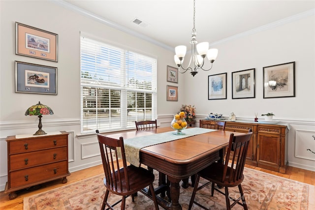 dining space featuring ornamental molding, a notable chandelier, and light hardwood / wood-style flooring