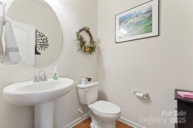 bathroom featuring toilet, sink, and hardwood / wood-style flooring