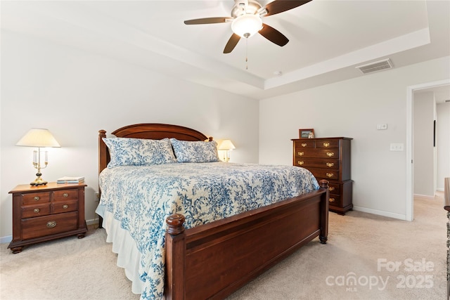 bedroom with light colored carpet, ceiling fan, and a tray ceiling