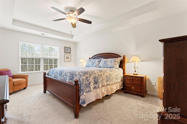 carpeted bedroom featuring ceiling fan and a tray ceiling