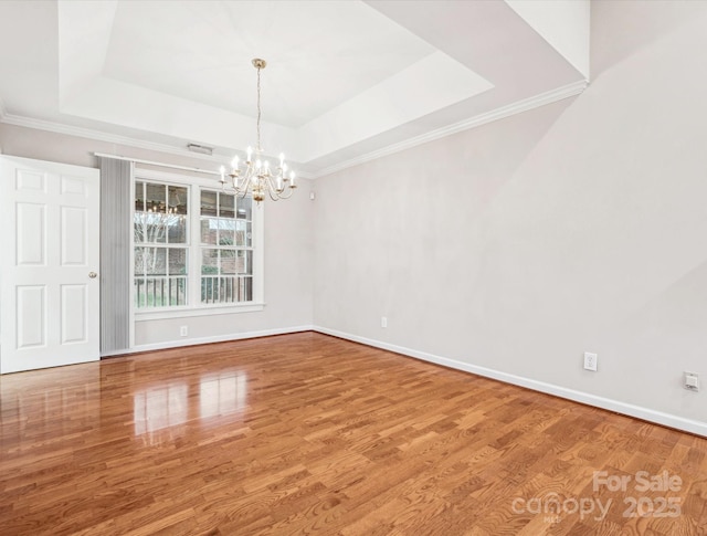 unfurnished dining area featuring wood-type flooring, a tray ceiling, and a notable chandelier