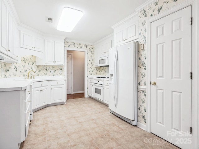 kitchen featuring white appliances, white cabinetry, and crown molding