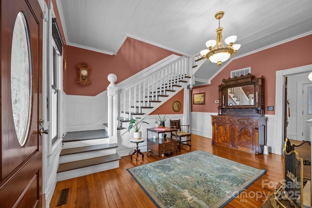 foyer featuring an inviting chandelier, ornamental molding, hardwood / wood-style floors, and plenty of natural light