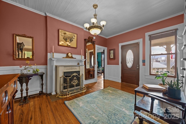 entrance foyer with hardwood / wood-style flooring, crown molding, and an inviting chandelier