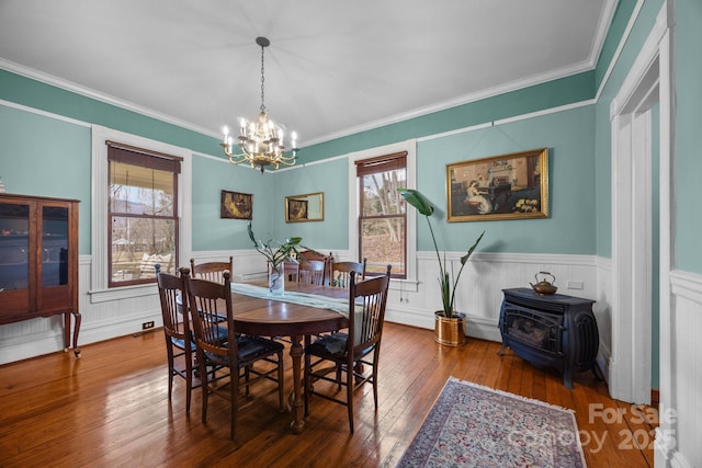 dining space featuring plenty of natural light, a chandelier, wood-type flooring, and a wood stove