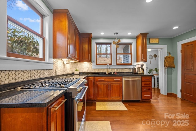 kitchen with sink, stainless steel appliances, dark hardwood / wood-style floors, decorative backsplash, and dark stone counters