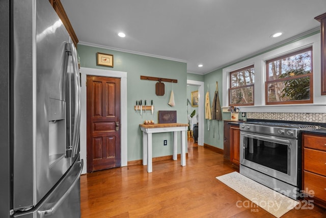 kitchen with stainless steel appliances, ornamental molding, and light hardwood / wood-style floors