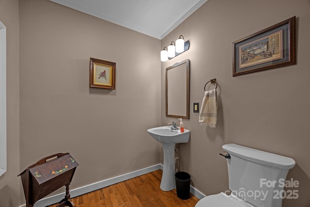 bathroom with crown molding, wood-type flooring, and toilet