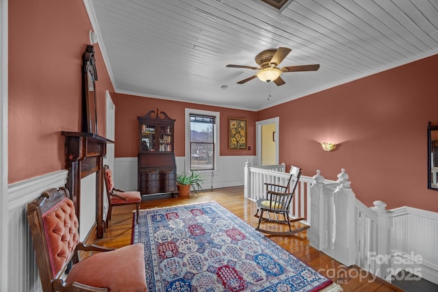 sitting room with wood ceiling, ceiling fan, ornamental molding, and light wood-type flooring