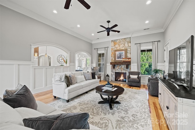 living room featuring ornamental molding, a healthy amount of sunlight, a fireplace, and light hardwood / wood-style flooring