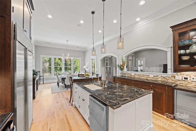 kitchen featuring appliances with stainless steel finishes, white cabinetry, decorative backsplash, decorative light fixtures, and dark stone counters