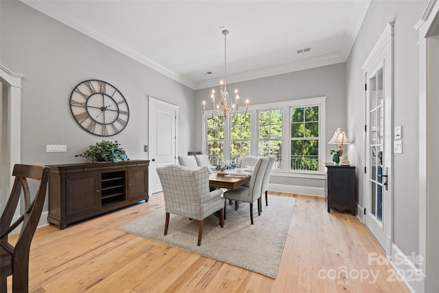 dining area featuring ornamental molding, a chandelier, and light hardwood / wood-style flooring