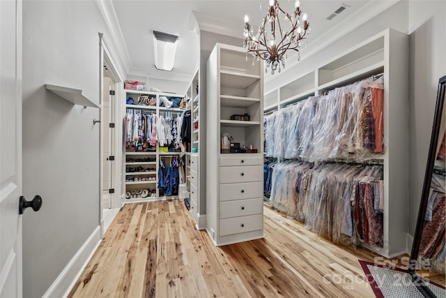 spacious closet with a chandelier and light hardwood / wood-style floors