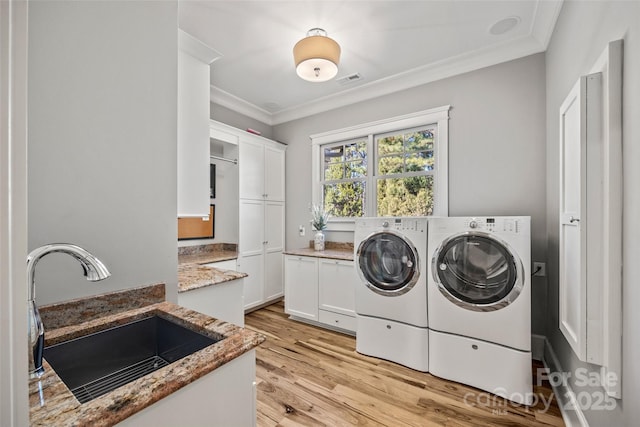 washroom with sink, crown molding, washer and clothes dryer, cabinets, and light wood-type flooring