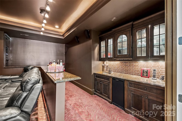 bar featuring light stone counters, dark brown cabinetry, a raised ceiling, and backsplash