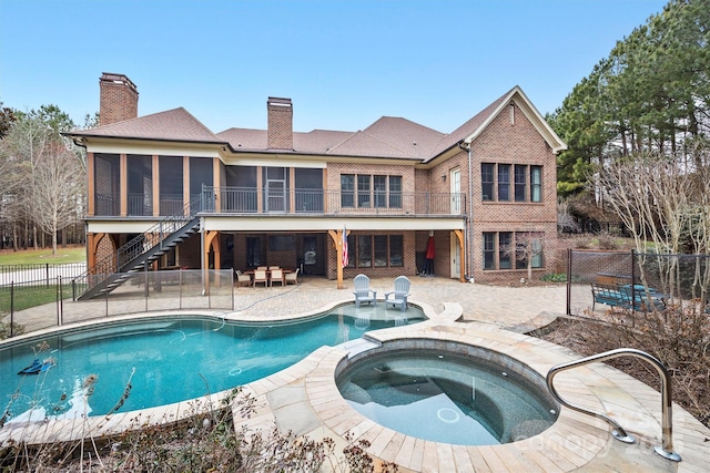 view of pool featuring an in ground hot tub, a patio, and a sunroom