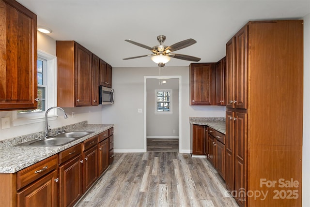 kitchen featuring ceiling fan, light wood-type flooring, and sink