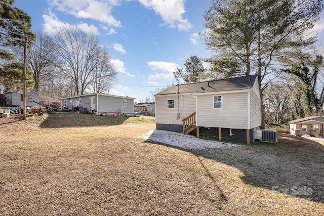 rear view of property with central air condition unit and a yard