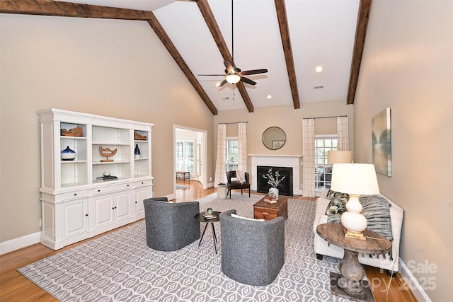 living room with high vaulted ceiling, ceiling fan, a wealth of natural light, and light hardwood / wood-style flooring