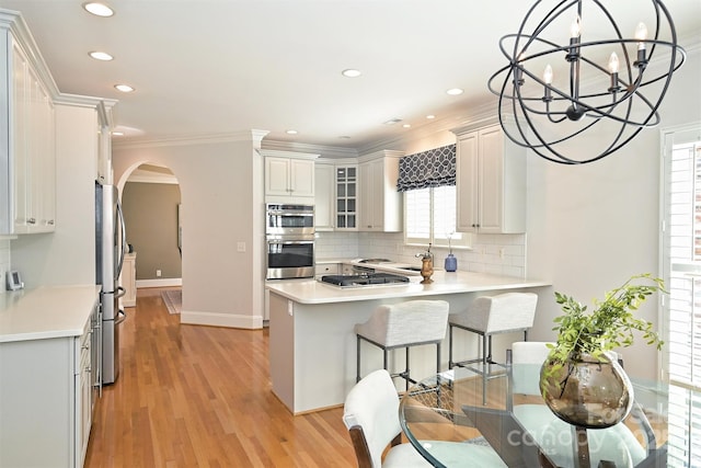 kitchen featuring kitchen peninsula, white cabinets, a healthy amount of sunlight, and appliances with stainless steel finishes