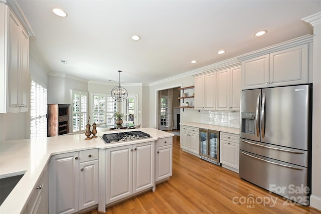 kitchen with white cabinetry, hanging light fixtures, wine cooler, crown molding, and appliances with stainless steel finishes