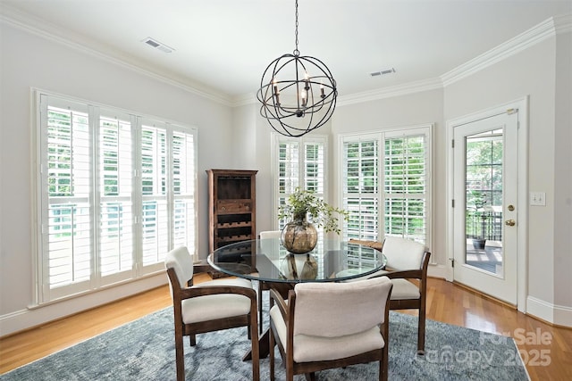 dining area with hardwood / wood-style floors, plenty of natural light, crown molding, and an inviting chandelier