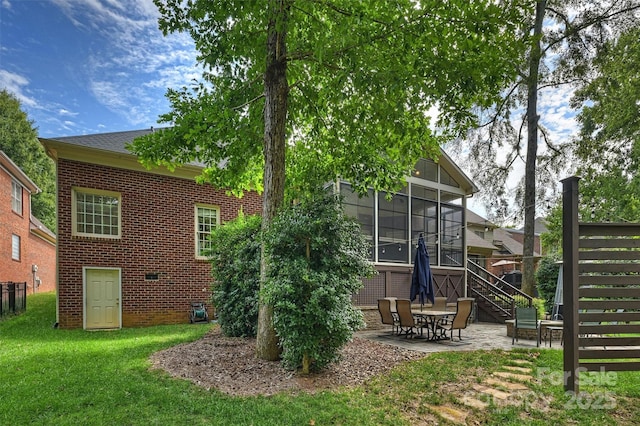 back of property with a lawn, a sunroom, and a patio area