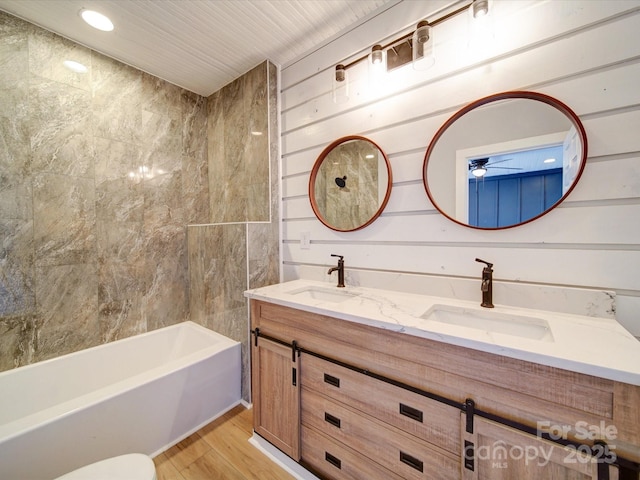 bathroom with vanity, hardwood / wood-style floors, wooden walls, and bathtub / shower combination