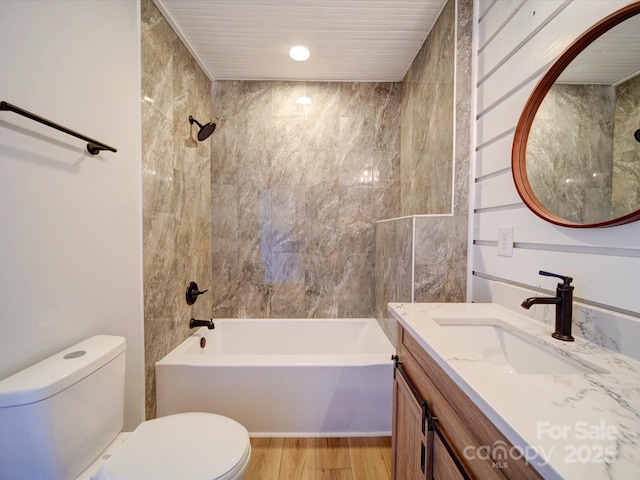 full bathroom with tiled shower / bath combo, vanity, hardwood / wood-style floors, and toilet