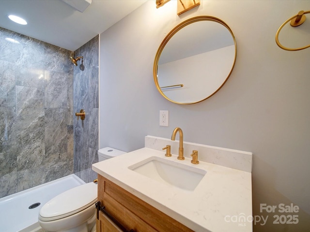 bathroom with vanity, tiled shower, and toilet