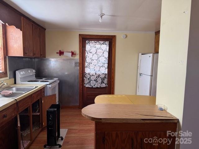 kitchen featuring sink, wood-type flooring, and white appliances