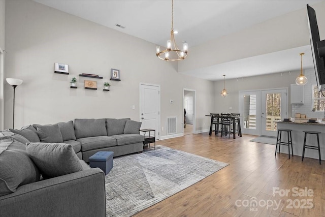 living room with hardwood / wood-style flooring, a chandelier, and french doors