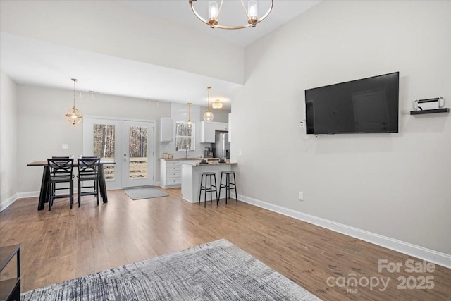 unfurnished living room featuring light hardwood / wood-style flooring, french doors, and an inviting chandelier