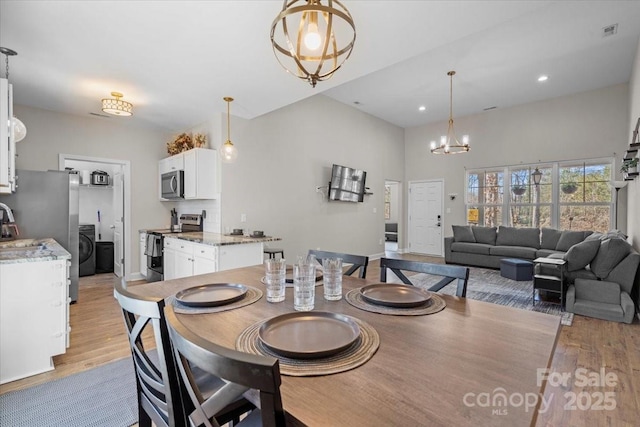 dining area featuring light hardwood / wood-style floors, a notable chandelier, and washer / clothes dryer