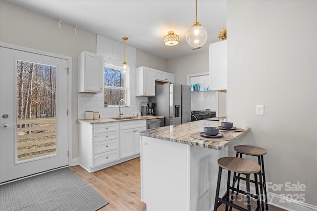 kitchen with white cabinets, stainless steel appliances, a kitchen breakfast bar, and sink