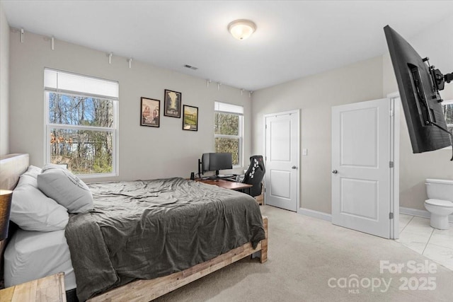 carpeted bedroom featuring multiple windows and connected bathroom