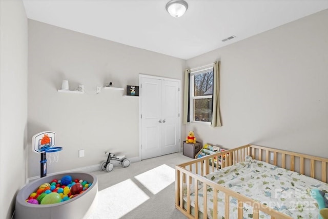 carpeted bedroom with a closet and a nursery area