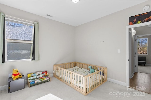 carpeted bedroom with a nursery area and multiple windows