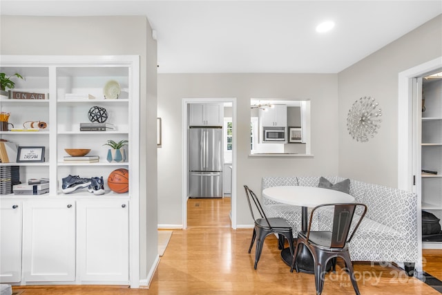 dining space featuring breakfast area, light hardwood / wood-style floors, and built in shelves