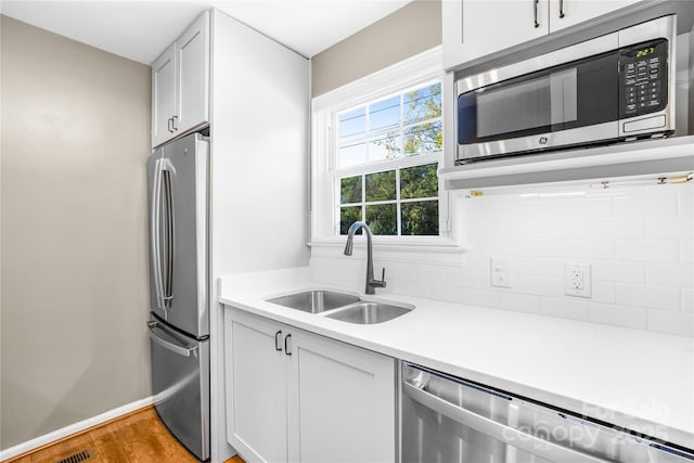 kitchen featuring white cabinets, appliances with stainless steel finishes, light hardwood / wood-style flooring, and sink